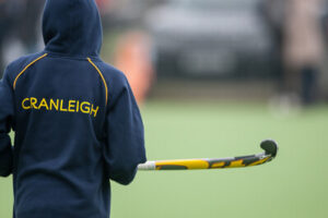 Back of Cranleigh School pupil holding a hockey stick