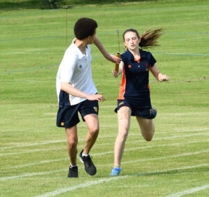 Cranleigh School girl passing baton on to boy in House Athletics relay run, 2021